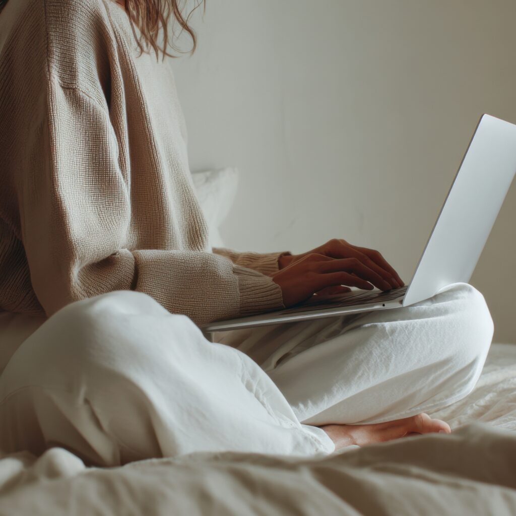 A mother sitting quietly with a laptop, reflecting and working calmly after stepping away from homeschool urgency