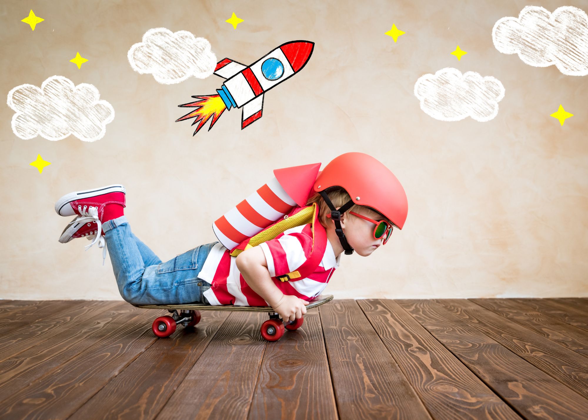 Child in a toy rocket costume riding a skateboard on a wood floor, with hand-drawn clouds and stars in the background.