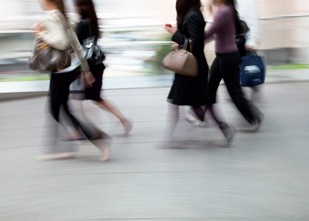 Group of people walking quickly with motion blur in an urban hallway.