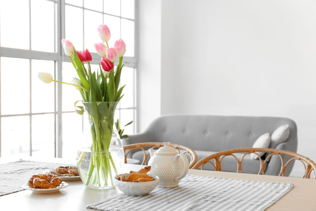 	A sunlit, quiet luxury table set with a vase of tulips and simple breakfast items, illustrating a peaceful simple homeschool morning routine.