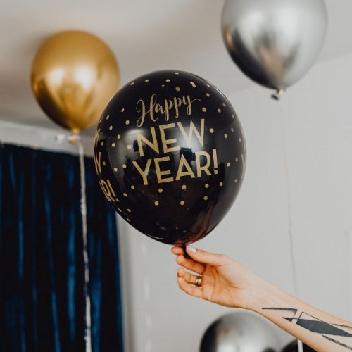 A hand holding a black “Happy New Year” balloon, symbolizing gentle after Christmas homeschool creativity and the quiet transition toward the new year.