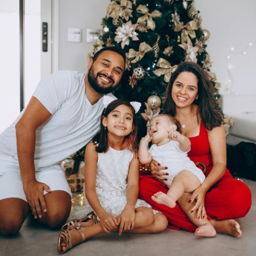 A smiling family sitting together near a decorated Christmas tree, reflecting the warmth of creative winter homeschool inspiration.