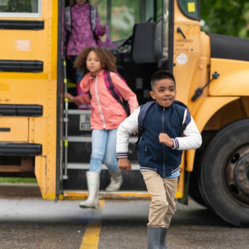 Children step off a school bus, illustrating the transition families face when learning how to notify the school when withdrawing from public school.