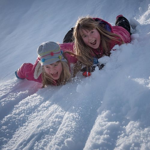 Two children playing joyfully in fresh winter snow, reflecting the need for December homeschool mother encouragement.