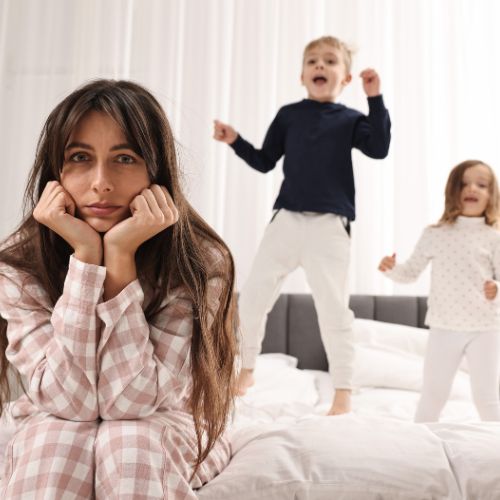 A homeschool mother feeling discouraged while her children play nearby, representing invisible progress and not being behind in homeschool