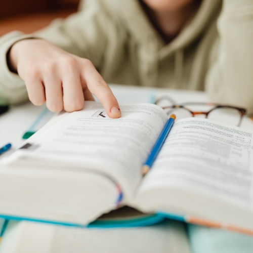 Child pointing to a page while reading a book during homeschool learning